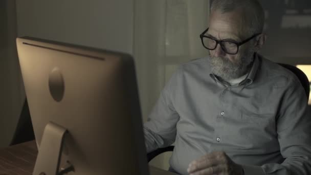 Tired senior man working with his computer at night - Video, Çekim
