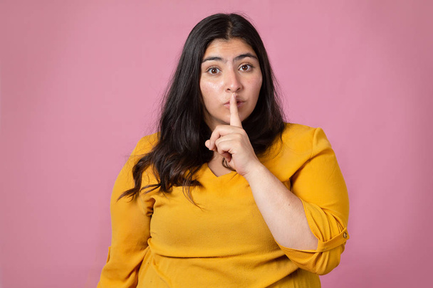 pretty latin woman making silence gesture on pink background - Photo, image