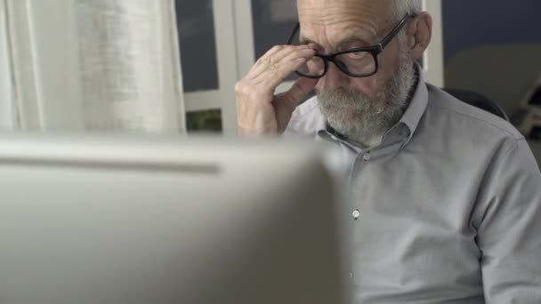 Hombre mayor trabajando con computadora y sintiéndose cansado
 - Metraje, vídeo