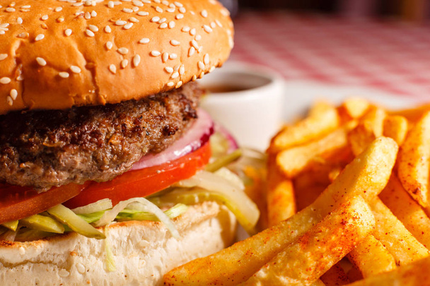 Uzavřete chutný Burger v restauraci. Sesame houska, maso Patty, rajčata, salát a okurka. Podávané s hranolky - Fotografie, Obrázek