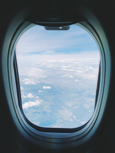 Plane window view with blue sky and clouds.   - Zdjęcie, obraz
