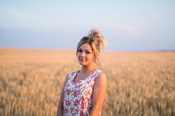Günbatımında sarı buğday tarlasında giyinmiş genç, baştan çıkarıcı, kırsal sarı saçlı kadın. - Fotoğraf, Görsel
