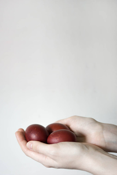 Unrecognizable women hand holding up three eggs. Knocking a red Easter egg. Old holiday tradition. Isolated on white background. Text empty space. Happy Easter! - Fotoğraf, Görsel