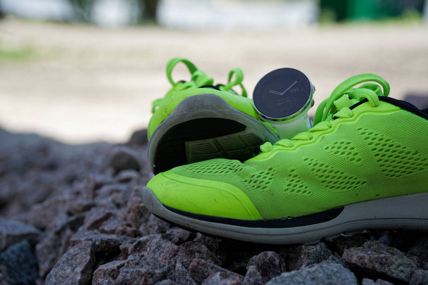 Reloj deportivo para crossfit y triatlón en las zapatillas de running verdes. Reloj inteligente para el seguimiento de la actividad diaria y el entrenamiento de fuerza
. - Foto, imagen