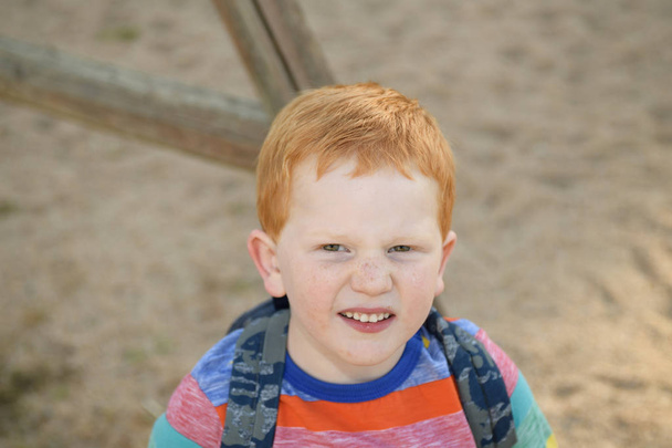 5-летний рыжеволосый портрет счастливого мальчика. Он смотрит в камеру.
 - Фото, изображение