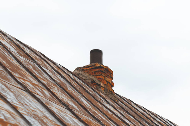 металлическая крыша, краска почти исчезла. на дымоходе. труба и керпич
. - Фото, изображение