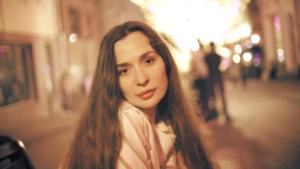 Portrait of a beautiful young woman on illuminated pedestrian area background - Video