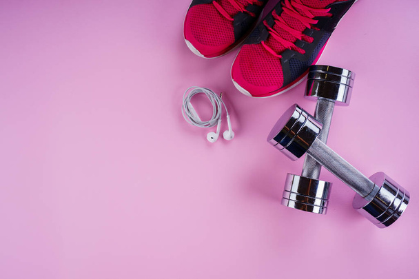 спортивная концепция: кроссовки, гантели, наушники на розовом бэкгре
 - Фото, изображение