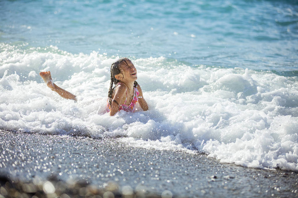 Heureuse jeune fille jouant dans les vagues sur la plage
 - Photo, image