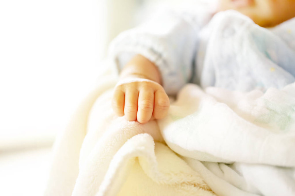 Newborn baby on a white and light blue blanket - tiny baby hand. - Foto, immagini