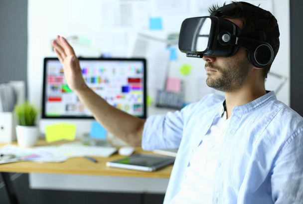 Jonge mannelijke software programmeur testen van een nieuwe app met 3D virtual reality bril op kantoor. - Foto, afbeelding