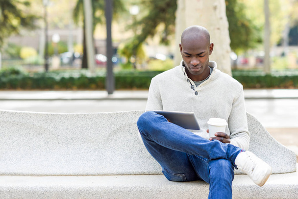 Schwarzer junger Mann mit Tablet-Computer und Kaffee zum Mitnehmen - Foto, Bild