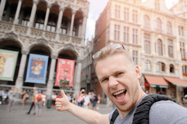 Hombre feliz viajero con mochila tomando foto selfie en la plaza central Bruselas, Bélgica
 - Foto, imagen