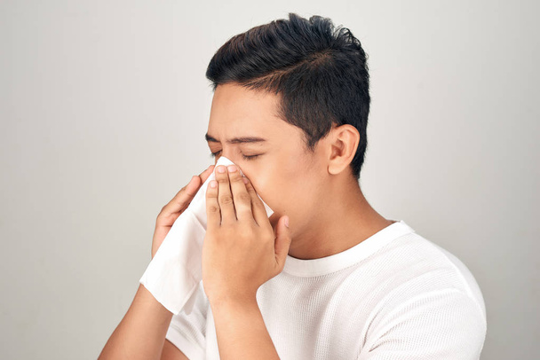 Closeup of sick Asian man blowing nose into tissue, suffering fr - Fotografie, Obrázek