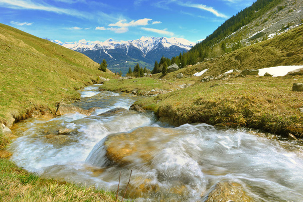 agua de un arroyo alpino que fluye en la montaña y picos nevados fondo
  - Foto, Imagen