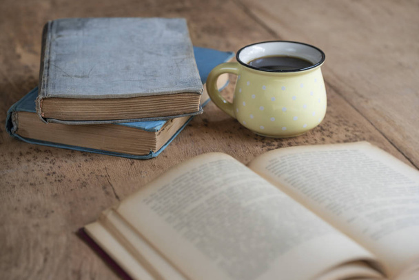 a cup of coffee and old books on a wooden table - Foto, imagen
