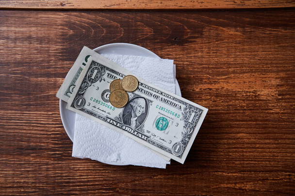 Restaurant tips or gratuity. Banknotes and coins on a plate - Фото, изображение