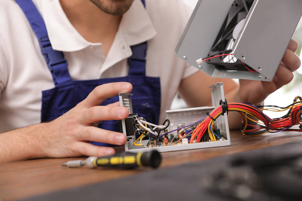 Male technician repairing power supply unit at table, closeup - Foto, afbeelding
