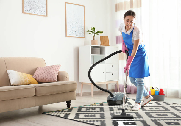 Woman hoovering carpet in living room. Cleaning service - Foto, Bild