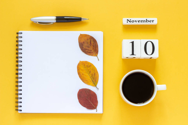 calendar November 10 cup of coffee, notepad with pen and yellow leaf on yellow background - Φωτογραφία, εικόνα