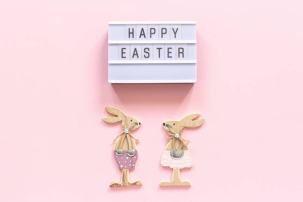 Lightbox text Happy Easter and pair of wooden bunnies on pink paper background. Concept Easter Creative top-down composition Flat lay Greeting card - Photo, Image