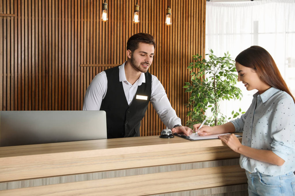 Receptionist registering client at desk in lobby - Photo, image