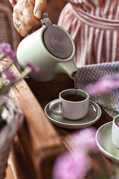 A woman pours tea into a mug of tea. Cozy atmosphere and homemad - Valokuva, kuva