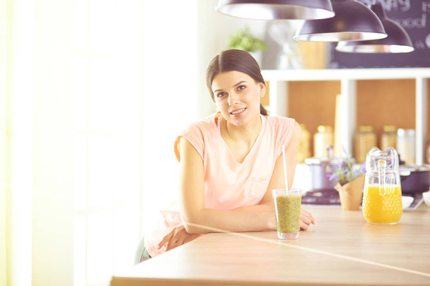 Young woman sitting a table in the kitchen - Fotoğraf, Görsel