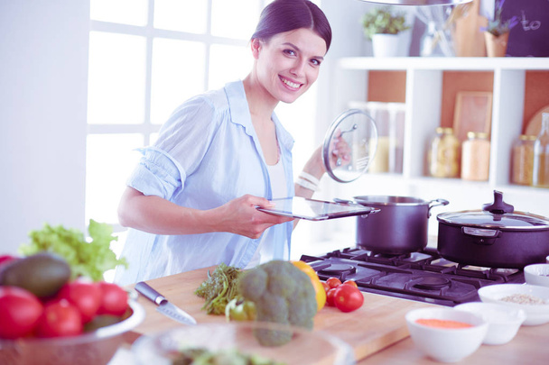 Young woman standing by the stove in the kitchen - Foto, imagen