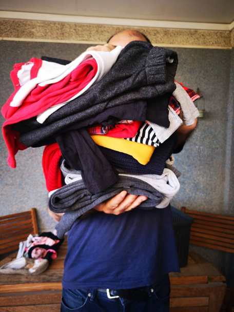A MAN SHOWING STACKED CLOTHING - Photo, Image