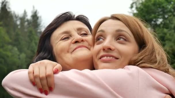 На відкритому повітрі крупним планом портрет усміхненої щасливої кавказької старшої матері зі своєю дорослою дочкою обіймає і дивиться на камеру. Доросла дочка цілує матір, день матері
 - Кадри, відео