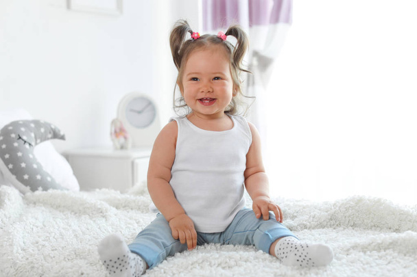 Adorable little baby girl sitting on bed in room - Foto, imagen