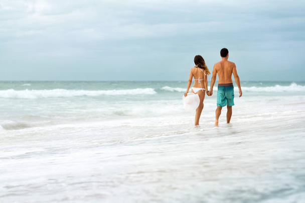 Молодая пара, идущая сквозь волны
 - Фото, изображение