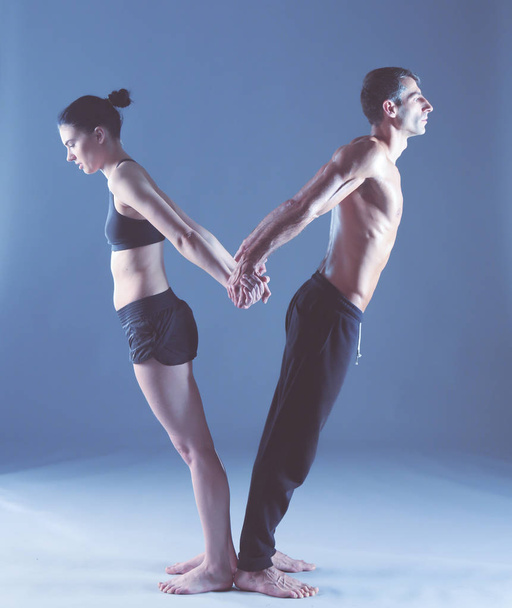 Young couple practicing acro yoga on mat in studio together. Acroyoga. Couple yoga. Partner yoga. - Foto, Bild