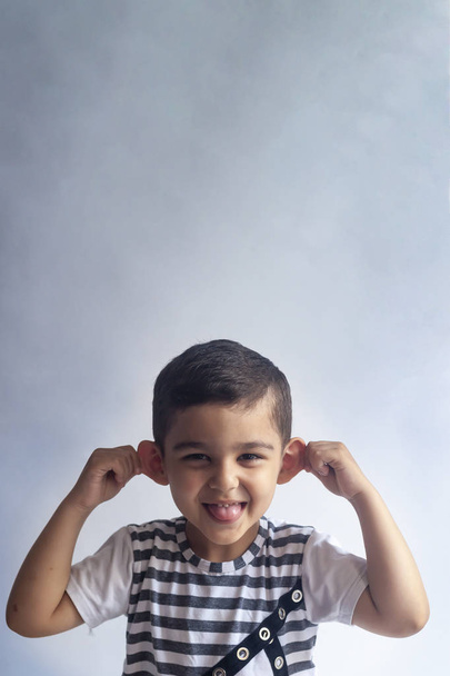 Six years boy portrait. Innocent smiling little boy on grey background. Little boy contorts his face. People, childhood lifestyle concept. - Photo, Image