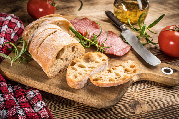 Italian ciabatta bread cut in slices with salami. - Foto, Imagem