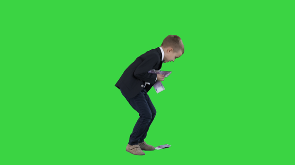 niedlicher Junge mit einem Bündel Euros, die ihm auf einem grünen Bildschirm aus den Händen fallen, Chroma-Schlüssel. - Filmmaterial, Video