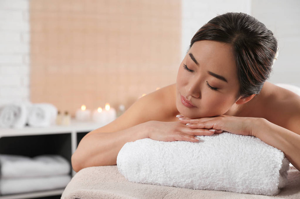Hermosa mujer asiática tumbada en la mesa de masaje en el salón de spa. Espacio para texto
 - Foto, imagen