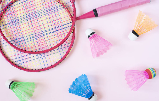 Badminton equipment. Badminton rackets and shuttlecocks on pink background. Top view, copy space - Foto, Imagem