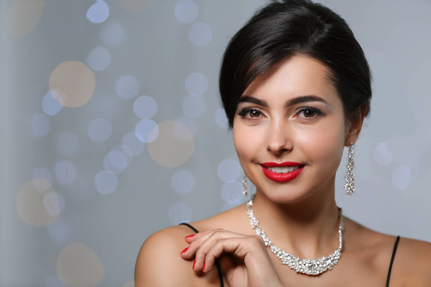 Beautiful woman with elegant jewelry on blurred background. Space for text - Φωτογραφία, εικόνα