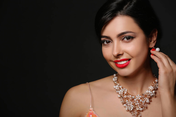 Beautiful young woman with elegant jewelry on dark background. Space for text - Φωτογραφία, εικόνα