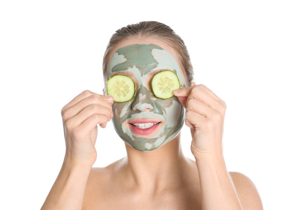 Beautiful woman with clay mask on her face holding cucumber slices against white background - Foto, Imagem