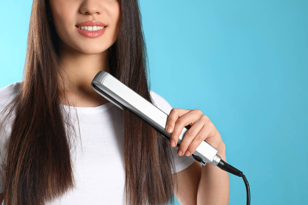 Happy woman using hair iron on color background, closeup - Foto, Imagem