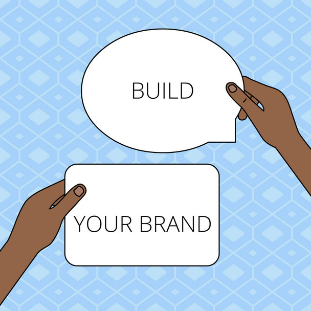 Pisanie notatki z Build Your Brand. Business photo showcasing zwiększenie kapitału marki za pomocą kampanii reklamowych Dwie cyfry Tabletki Znaki odbędzie się w rękach jeden nad drugim przestrzeni tekstowej. - Zdjęcie, obraz
