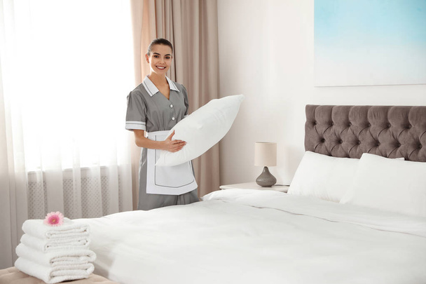 Young chambermaid making bed in hotel room. Space for text - Foto, Imagem