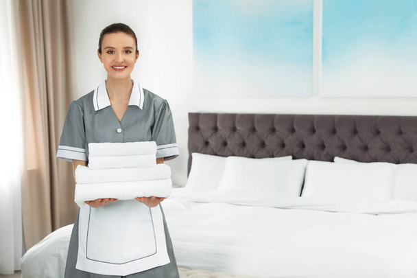 Chambermaid with stack of fresh towels in hotel room. Space for text - Photo, image