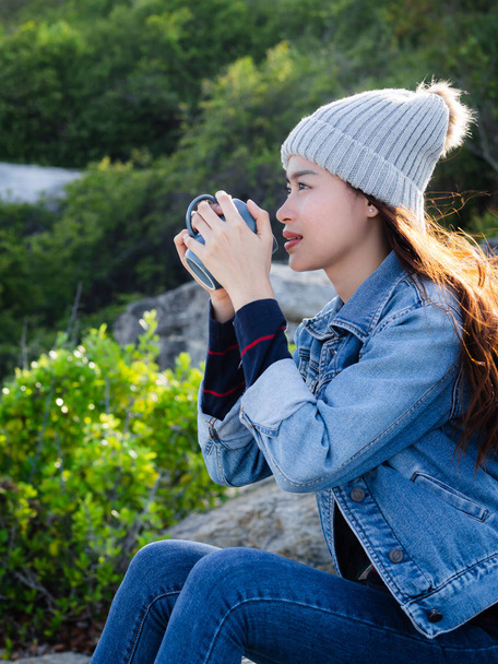 Счастливая азиатская женщина с кружкой кофе на фоне природы, камера
 - Фото, изображение