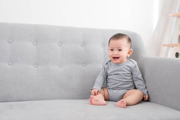 childhood, babyhood and people concept - happy little baby girl sitting on sofa at home - 写真・画像