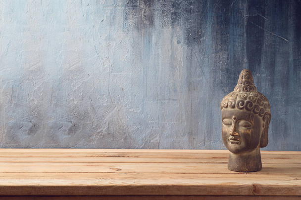 Estátua de Buda na mesa de madeira sobre fundo escuro
 - Foto, Imagem
