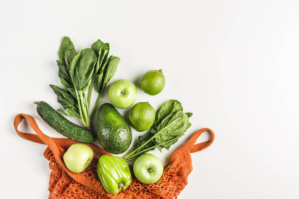 Green vegetables and fruits in orange string bag - Photo, Image